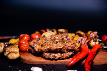 Steak on a wooden cutting board and black background sprinkled with salt and pepper.