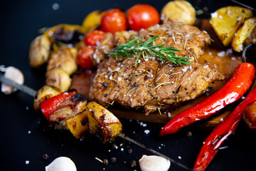 Steak on a wooden cutting board and black background sprinkled with salt and pepper.