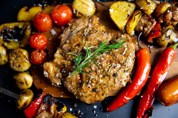 Steak on a wooden cutting board and black background sprinkled with salt and pepper.