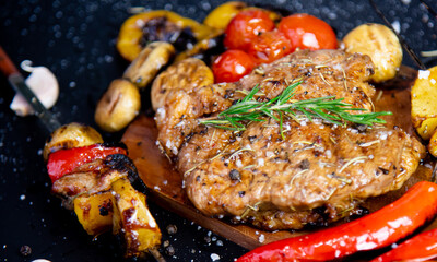 Steak on a wooden cutting board and black background sprinkled with salt and pepper.