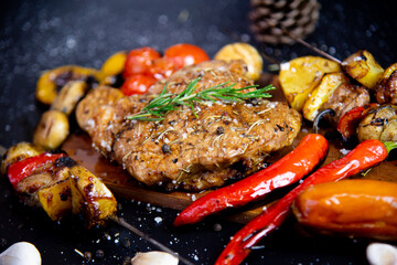 Steak on a wooden cutting board and black background sprinkled with salt and pepper.