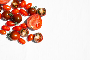 Red ripe tomatoes texture background. Different qualities of tomatoes on white linen tablecloth. Black tomato Solanum lycopersicum.