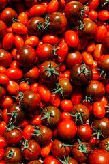 Red ripe tomatoes texture background. Different qualities of tomatoes on the wooden table. Black tomato Solanum lycopersicum.