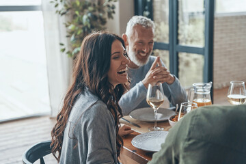 Happy family communicating and smiling while having dinner together - obrazy, fototapety, plakaty