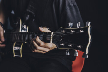 a guy in a dark T-shirt plays an electric guitar on a dark background