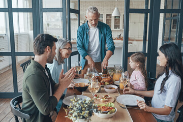 Happy multi-generation family communicating and smiling while having dinner together
