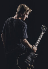 a guy in a dark T-shirt plays an electric guitar on a dark background