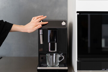 Woman pressing button on black coffee machine