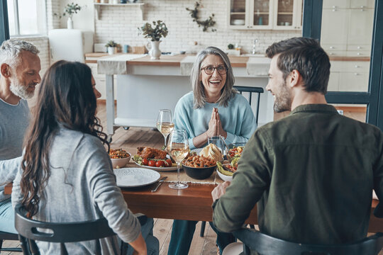 Modern Multi-generation Family Communicating And Smiling While Having Dinner Together