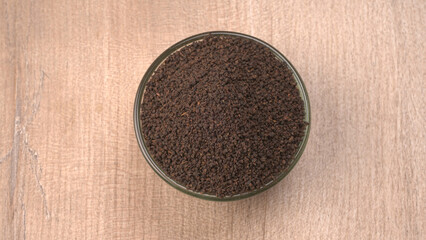 Black Tea Powder or dry dust tea powder, chai patti isolated in wooden bowl with Cardamom, Clove...