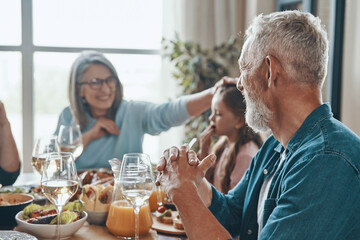 Happy multi-generation family communicating and smiling while having dinner together
