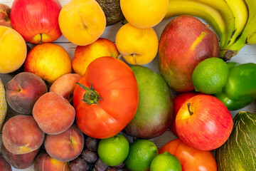 bulk fruits viewed from top view. Apples and limes, yellow peach trees, red peaches, bananas and mangoes, tomatoes and red grapes