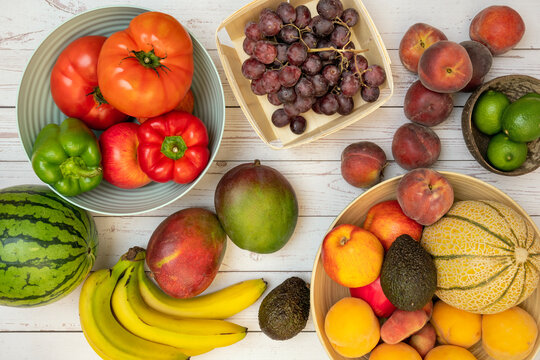Image of fruits and vegetables in fruit bowls or on the table. Ripe bananas, melons and watermelons, red grapes, nectarines and limes, tomatoes and peppers, African mangoes and Mexican avocados