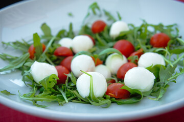Delicious and easy healthy eating - Italian caprese salad with mozzarella cheese, arugula, cherry tomatoes ans balsamic sauce