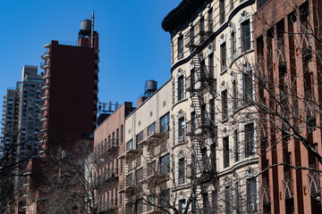 Obraz premium Row of Colorful Old Brick Residential Buildings on the Upper East Side of New York City with Fire Escapes