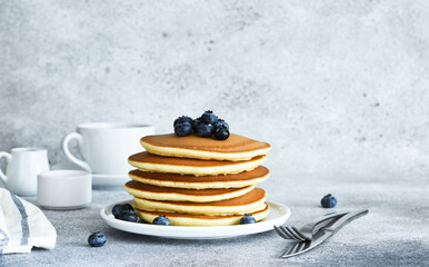 Homemade American pancakes with berries and maple syrup for breakfast on a concrete background.