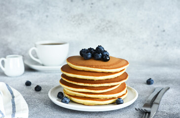 Homemade American pancakes with berries and maple syrup for breakfast on a concrete background.