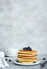 Homemade American pancakes with berries and maple syrup for breakfast on a concrete background.