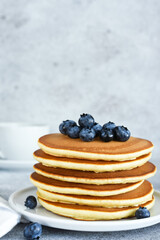Homemade American pancakes with berries and maple syrup for breakfast on a concrete background.