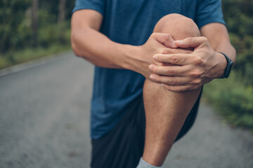 young man stretching in the park before running. Young man workout before fitness training at the park. Healthy and exercise young man warming up on the road in the forest.