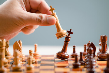 Hand with the wooden chess game, move white chess to attack the black rival and take the advantage on a chessboard, business strategy, business success, leadership concept