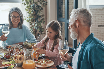 Happy multi-generation family communicating and smiling while having dinner together