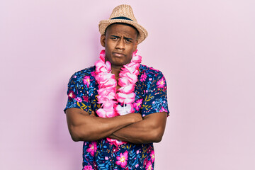Young black man wearing summer shirt and hawaiian lei skeptic and nervous, disapproving expression...