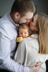 loving parents hold a baby and kiss. the happiness of fatherhood and motherhood.
