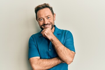 Middle age man wearing casual clothes smiling looking confident at the camera with crossed arms and hand on chin. thinking positive.