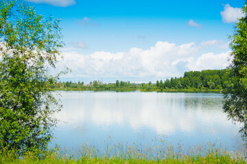 beautiful summer landscape. lake with reflective sky, forest and clouds..