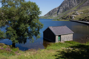 Llyn Ogwen, Ogwen lake, with building on the shore in Snowdonia National Park, North Wales.  On a summers day with blue sky
