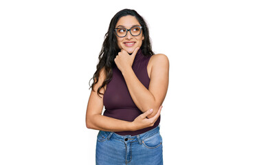 Brunette young woman wearing casual clothes and glasses with hand on chin thinking about question, pensive expression. smiling with thoughtful face. doubt concept.