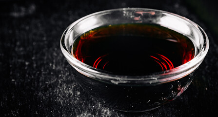 Soy sauce in small glass dish black background