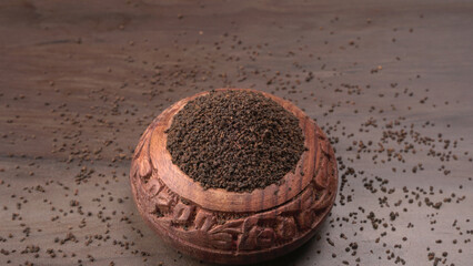 Black Tea Powder or dry dust tea powder, chai patti isolated in wooden bowl with Cardamom, Clove and Ginger.