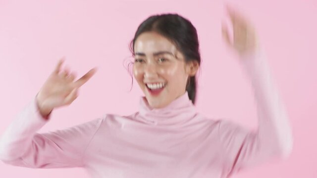 Beauty concept of 4k Resolution. Young Asian woman dancing with fun on a pink background.