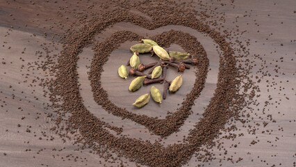 Black Tea Powder or dry dust tea powder, chai patti isolated in wooden bowl with Cardamom, Clove and Ginger.