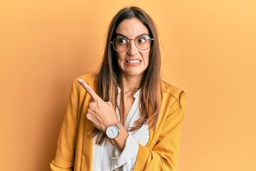 Young beautiful woman wearing business style and glasses pointing aside worried and nervous with...