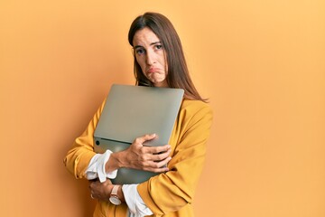 Young beautiful woman holding laptop depressed and worry for distress, crying angry and afraid. sad expression.