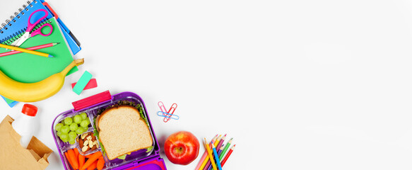 Healthy school lunch with school supplies. Overhead view corner border on a white banner background. Back to School concept.
