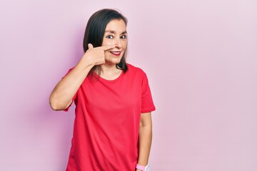 Middle age hispanic woman wearing casual clothes pointing with hand finger to face and nose, smiling cheerful. beauty concept