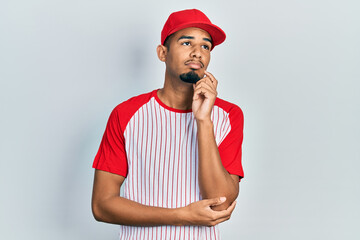 Young african american man wearing baseball uniform amazed and smiling to the camera while presenting with hand and pointing with finger.