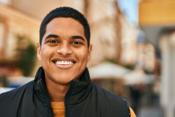 Young latin man smiling happy standing at the city