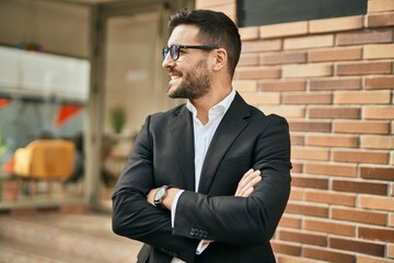 Young hispanic businessman with arms crossed smiling happy at the city.