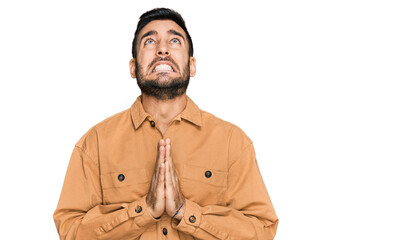 Young hispanic man wearing casual clothes begging and praying with hands together with hope expression on face very emotional and worried. begging.