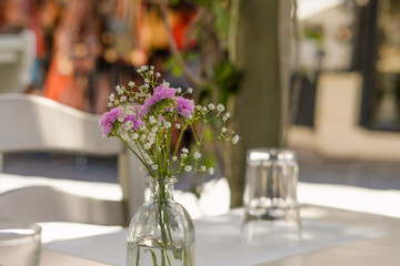 Field flowers in glass vase as dinner table decoration in street restaurant