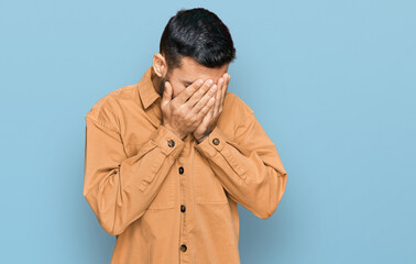 Young hispanic man wearing casual clothes with sad expression covering face with hands while crying. depression concept.