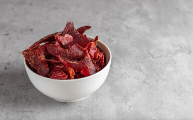 Jerky Beef, Jerky in white bowls on a concrete background. Rustic country style dried meat. Delicious meat snack.