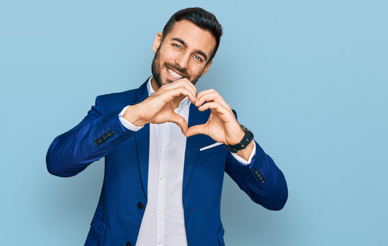 Young hispanic man wearing business jacket smiling in love doing heart symbol shape with hands. romantic concept.
