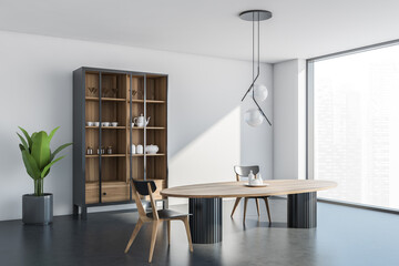 Corner view of light white dining room space with cupboard