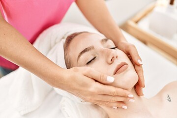 Fototapeta na wymiar Young caucasian woman relaxed reciving face massage at beauty center.
